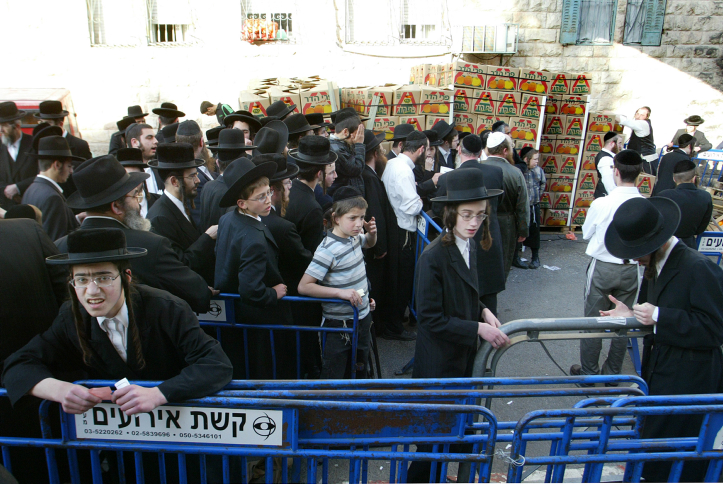 Ultra-Orthodox Jewish men queue at the entrance of a food distribution point for people in need in advance of the high Jewish holiday of Passover in Me'a She'arim